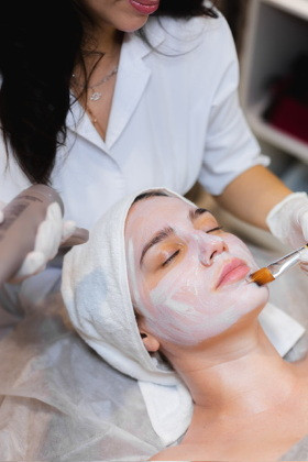 esteticista-com-um-pincel-aplica-uma-mascara-hidratante-branca-no-rosto-de-uma-jovem-cliente-em-um-salao-de-beleza-de-spa.jpeg